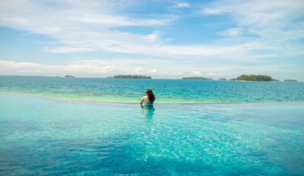 A woman relaxes in an infinity pool with a stunning ocean view.