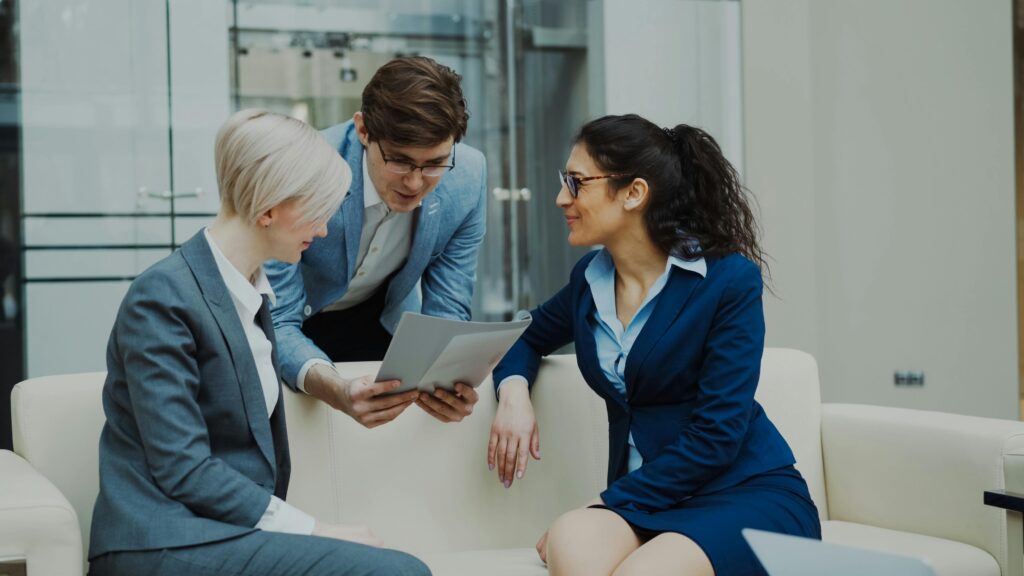 Three business professionals engaged in a meeting, collaborating over a tablet.