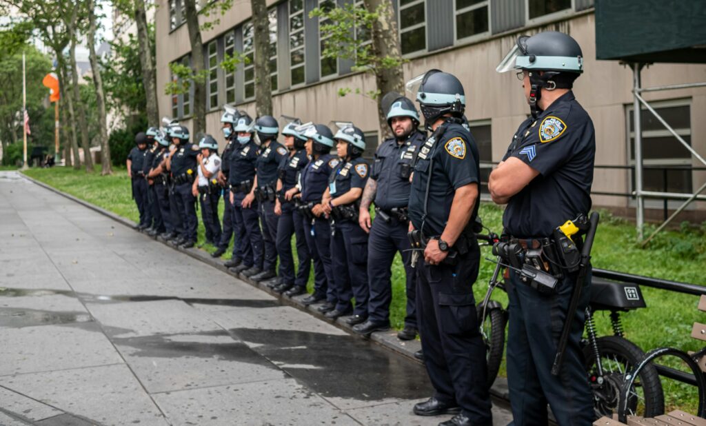 Police officers standing in line outside a building on a city sidewalk.