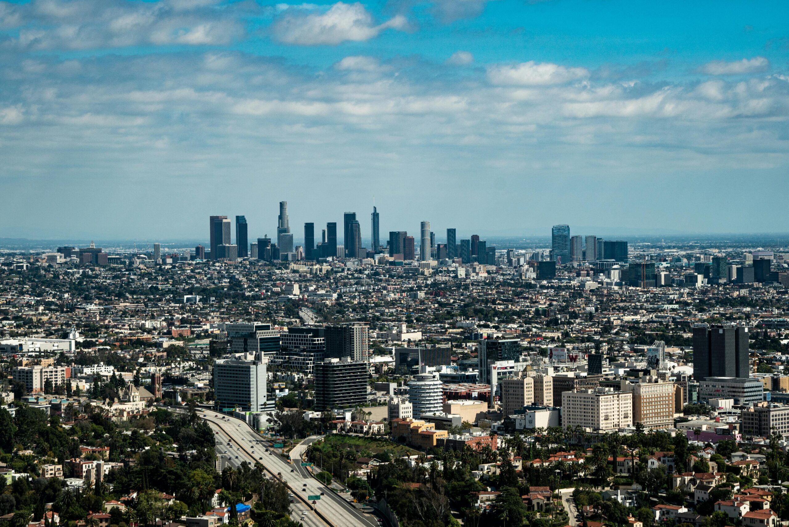 Stunning aerial view of Los Angeles skyline with skyscrapers under a blue sky.