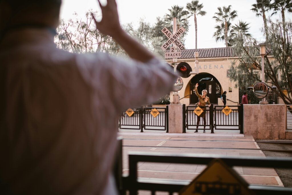 Two friends reunite at a train crossing, capturing a joyful moment in Pasadena.