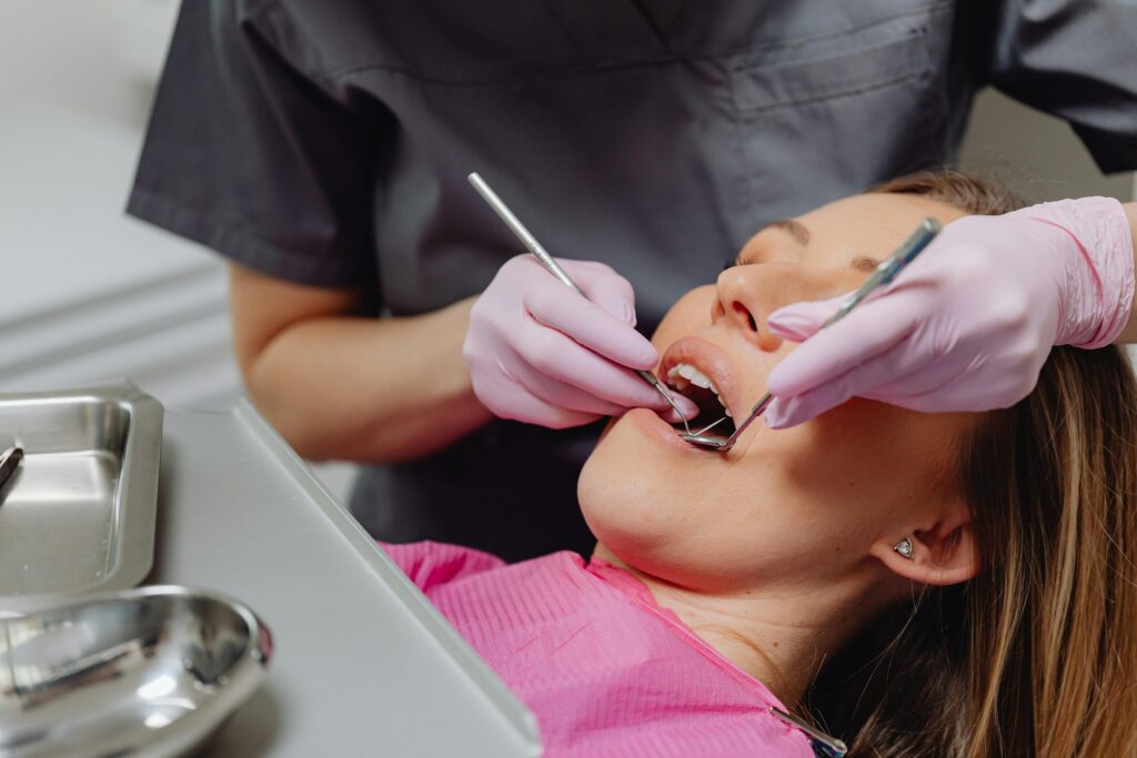 Close-up of a female patient receiving a dental checkup with modern tools in a clinical setting.