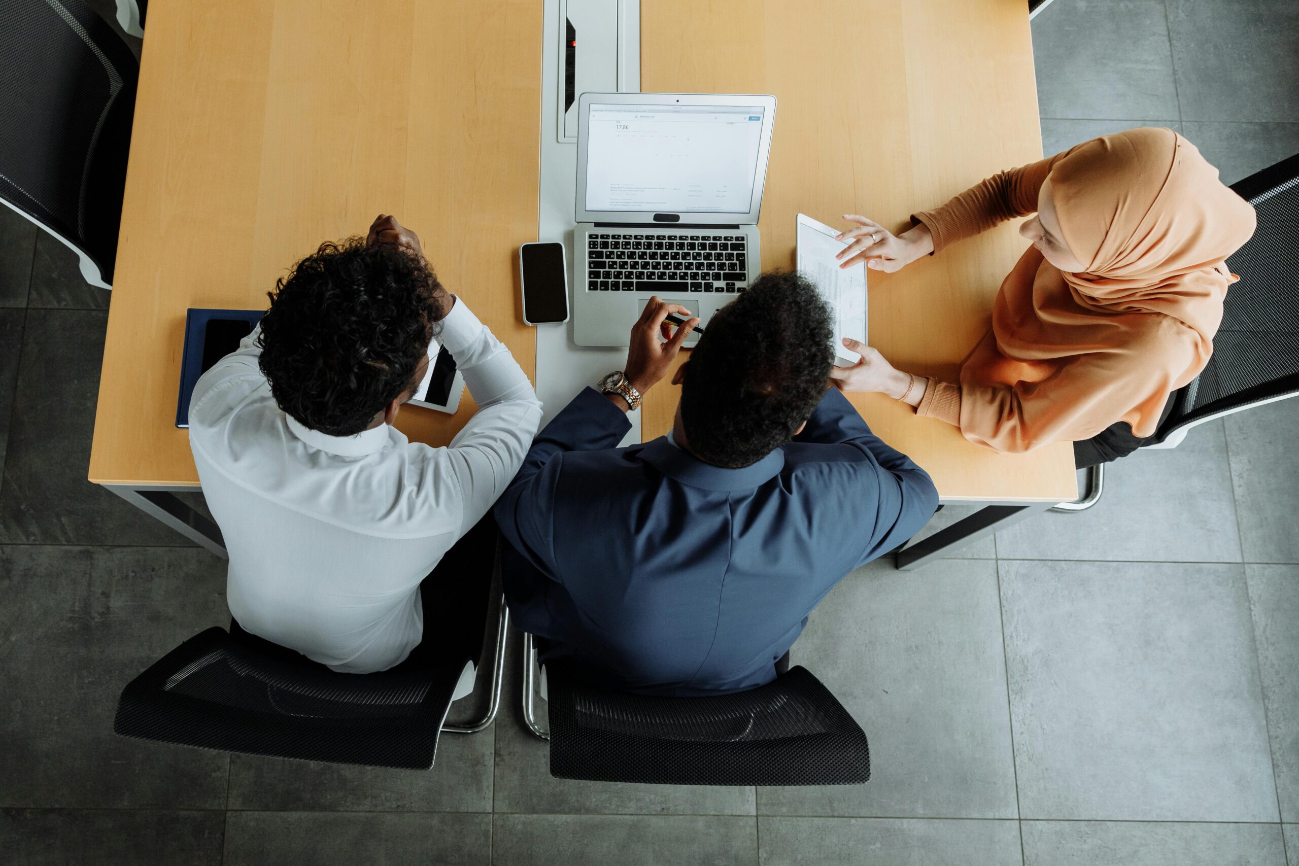 Overhead view of a diverse team working together on laptops at an office meeting.