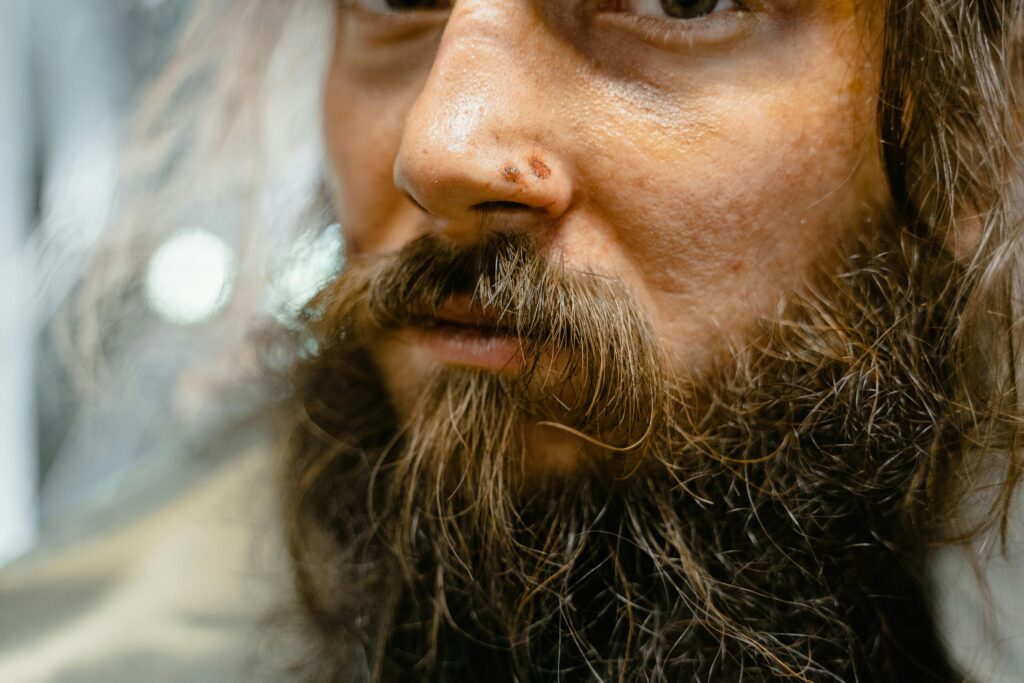 Close-up of a man's face with unkempt beard and facial hair, showcasing texture and detail.