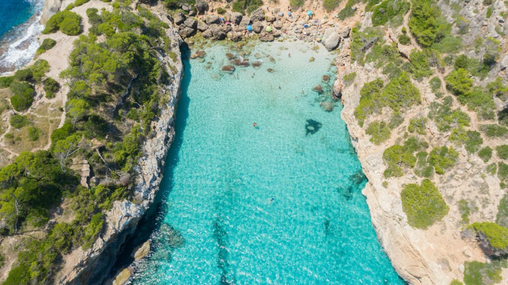 Breathtaking aerial view of Caló des Moro's turquoise waters and rocky shores in Mallorca, Spain.