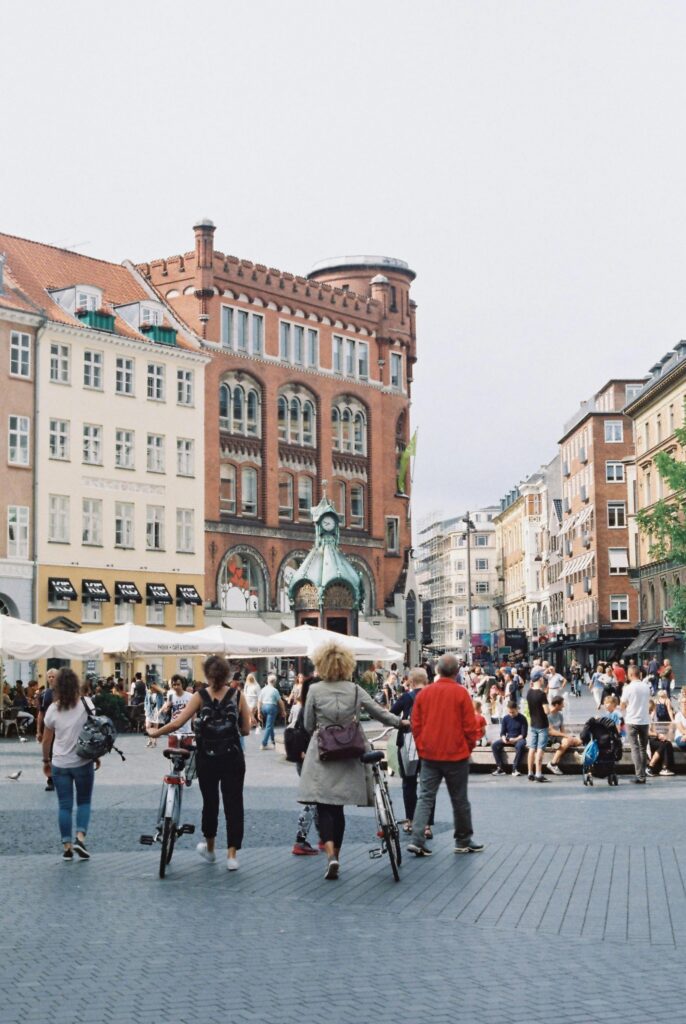 A bustling town square filled with people and bicycles, set against classic architecture.