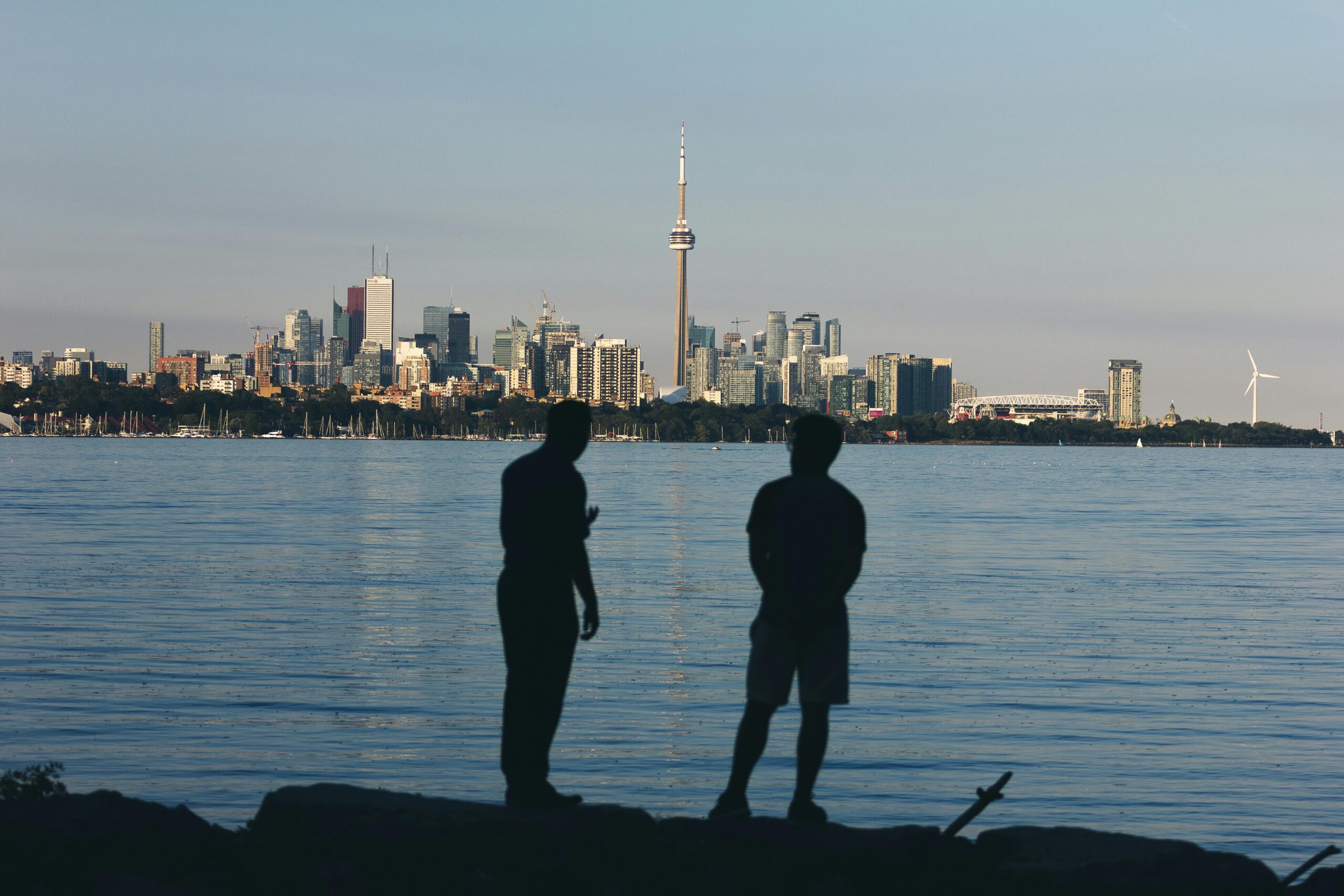 Silhouette of two people watching the Toronto skyline across the water at sunset.