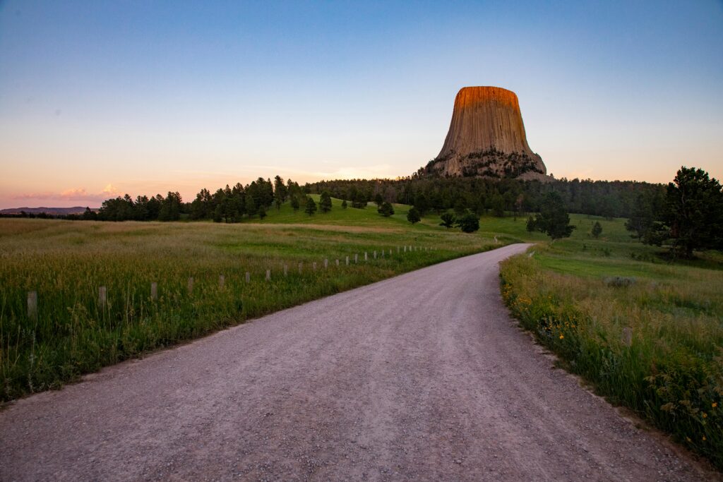 Beautiful sunset at Devils Tower, Wyoming with a winding road leading to the monument.