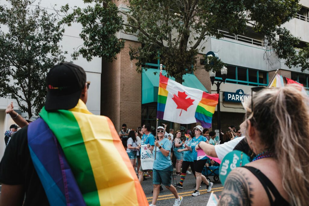 A lively pride parade with participants waving rainbow and Canadian flags, celebrating diversity and inclusivity.
