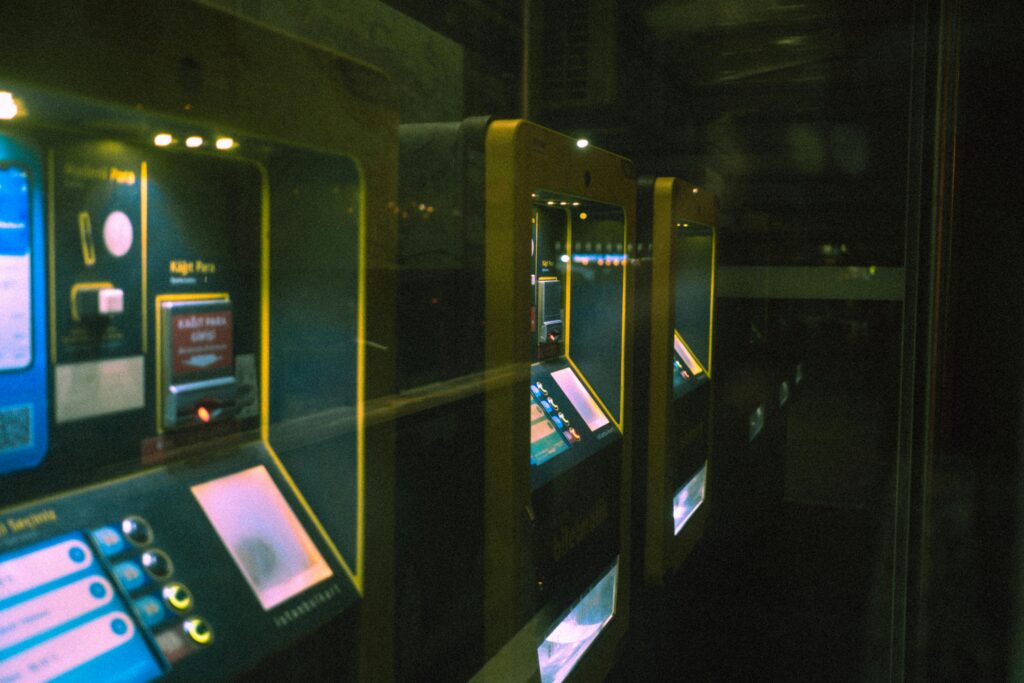 Row of illuminated ticket machines in a dark setting with a reflective perspective.