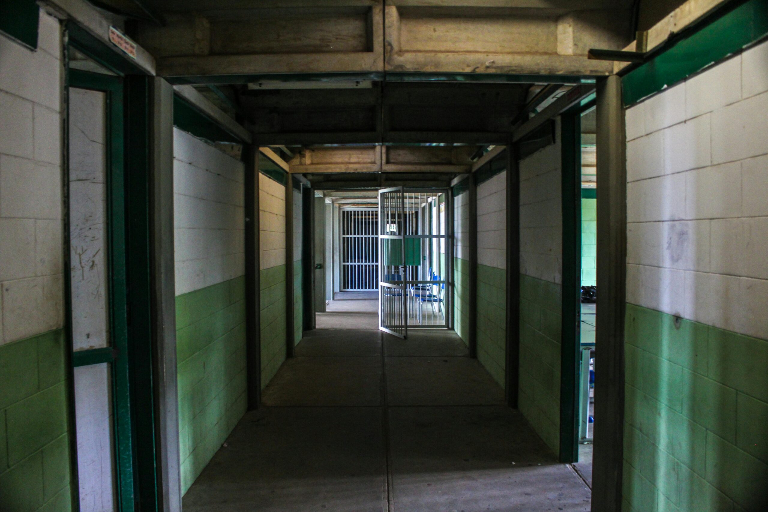 View of an empty prison corridor with open cell doors symbolizing security and isolation.