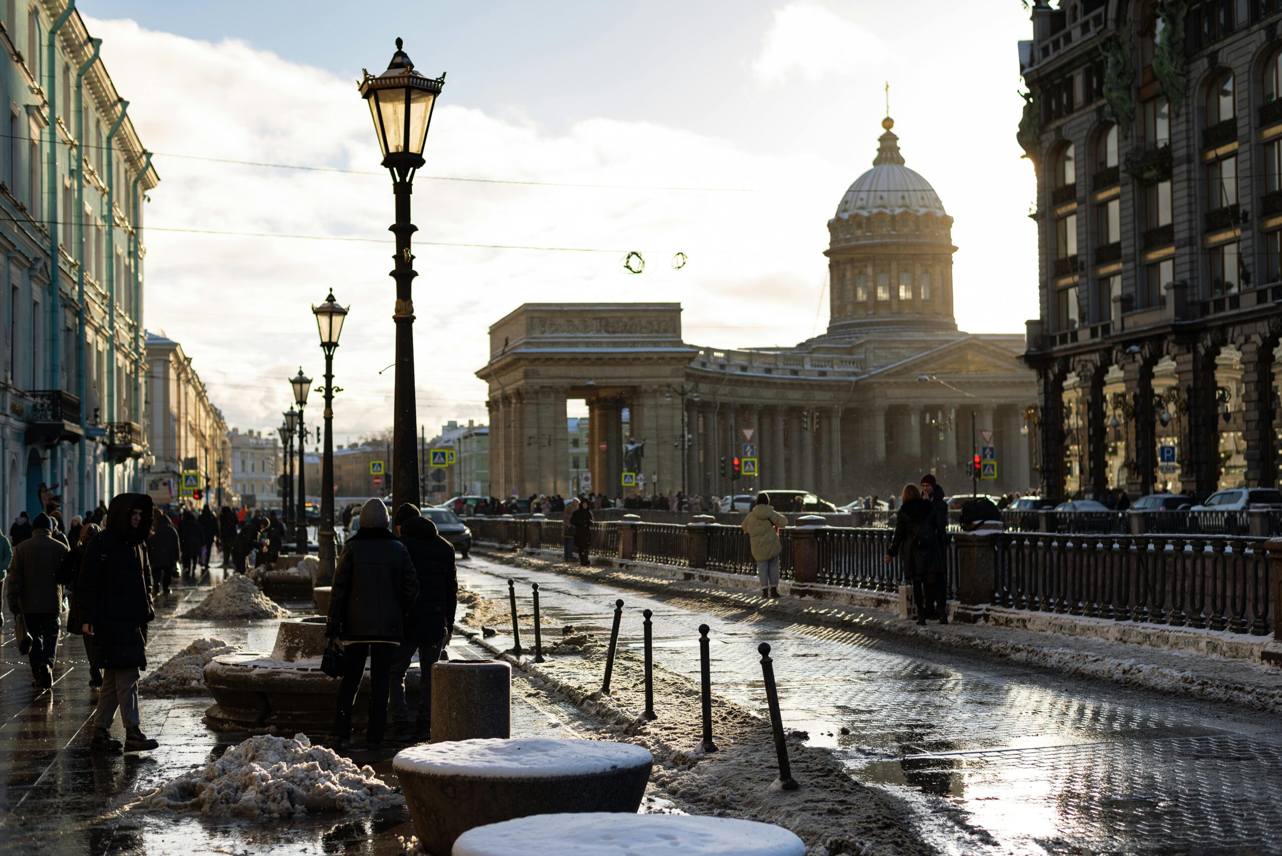 A winter scene near Kazan Cathedral with snow and pedestrians on a city street in Saint Petersburg.