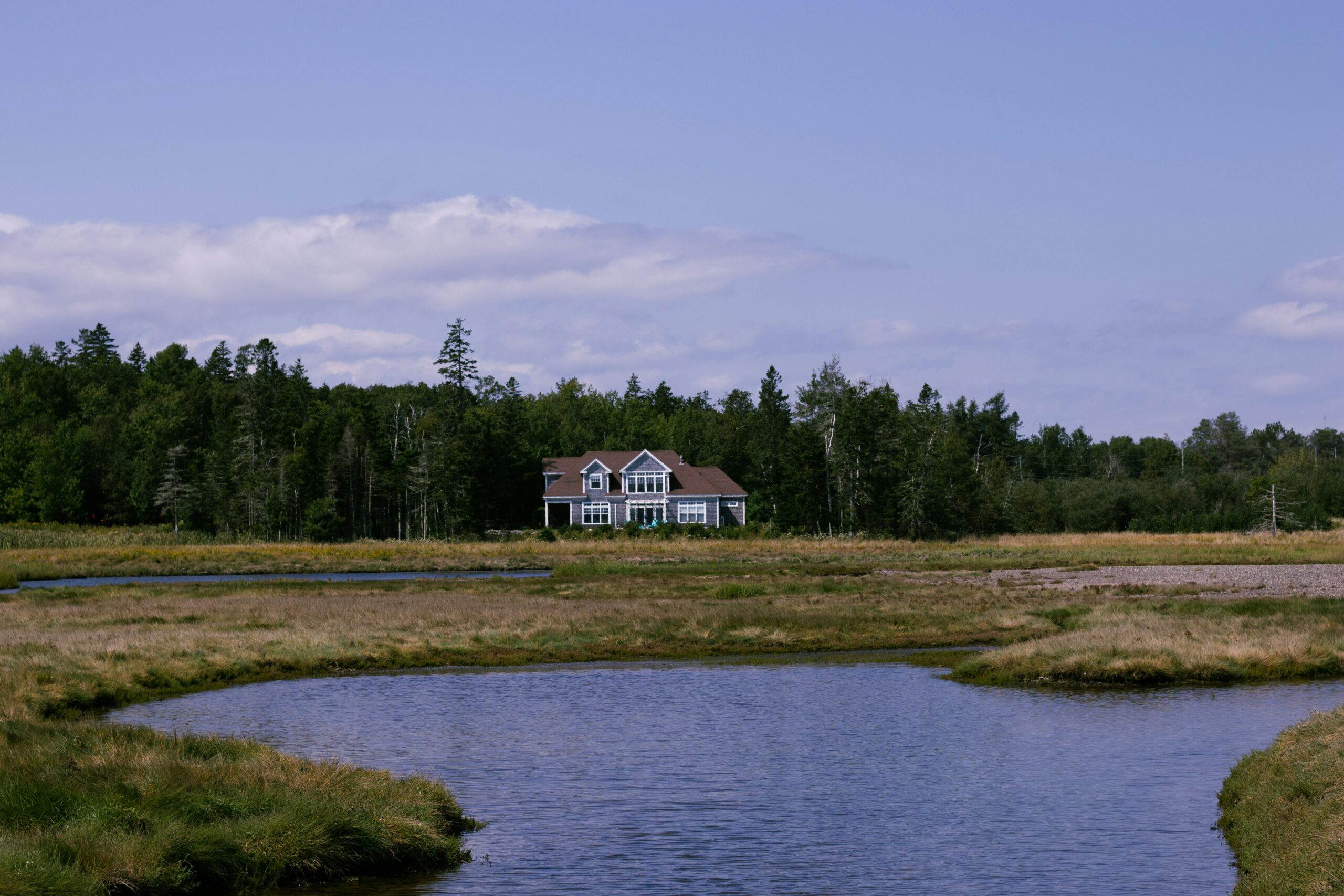 Charming rural landscape with a house by a meandering river in St. Andrews, Canada.
