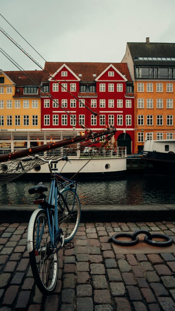 Scenic view of vibrant rowhouses by a canal with a bicycle and boat in foreground.