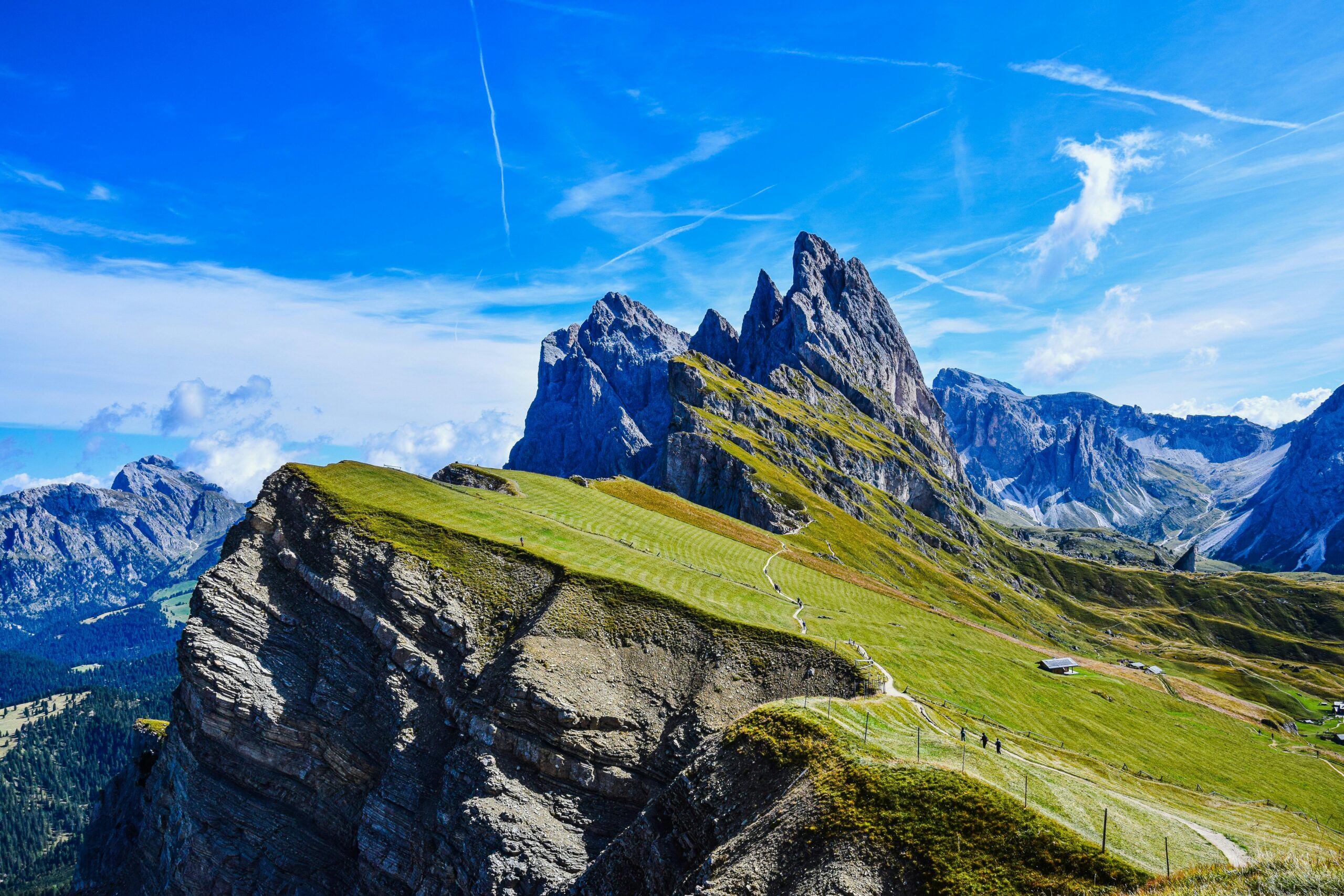 Stunning aerial view of the Dolomite peaks and lush meadows under a clear blue sky.