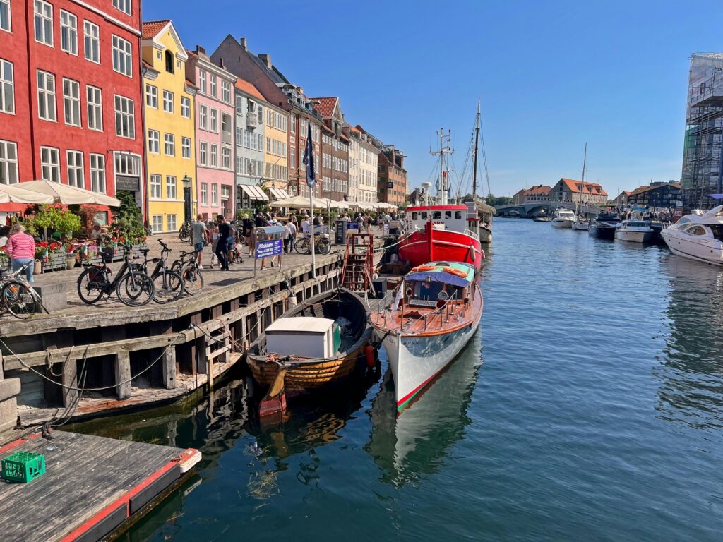 Colorful buildings and boats along Nyhavn canal in Copenhagen, Denmark, on a sunny day.