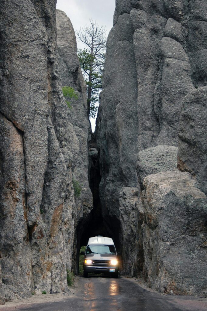 Van driving through a narrow rock gorge in Custer State Park, South Dakota.