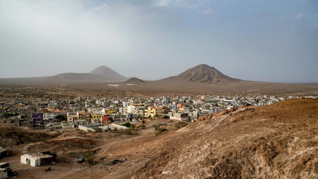 Aerial view of a city nestled in an arid landscape with distant mountains under a clear sky.