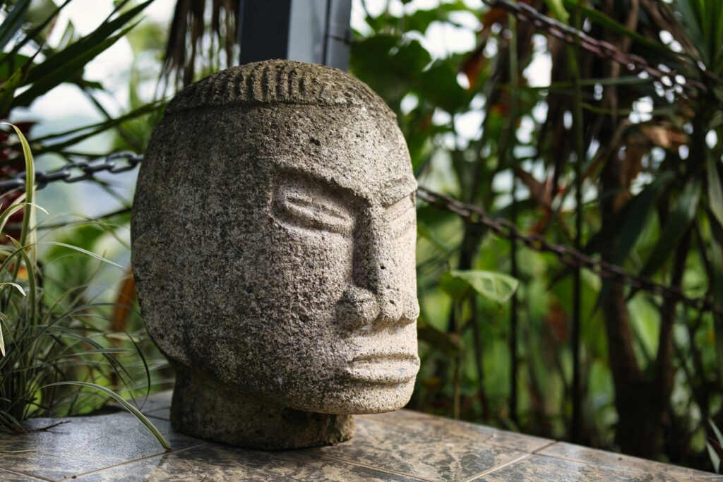 A detailed stone sculpture set in a lush outdoor garden in Ciudad Colón, Costa Rica.