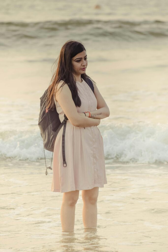 Thoughtful woman stands at the edge of Vagator Beach, Goa at sunset, embodying tranquility.