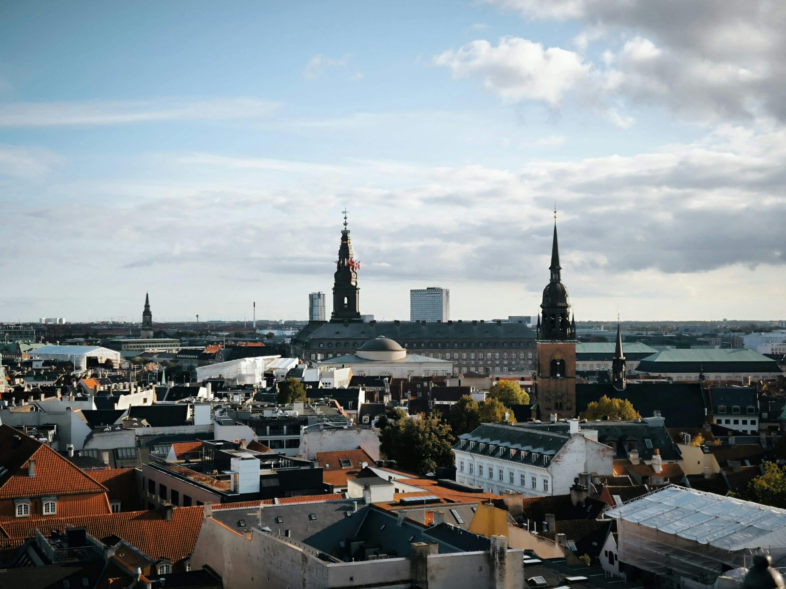 A stunning aerial view of Copenhagen's historic cityscape featuring prominent architectural landmarks under a blue sky.
