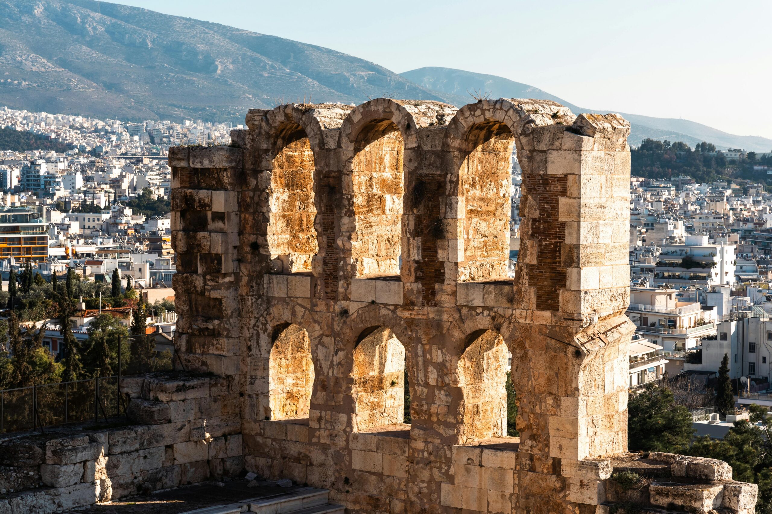 View of the ancient Odeon of Herodes Atticus in Athens with a cityscape backdrop.
