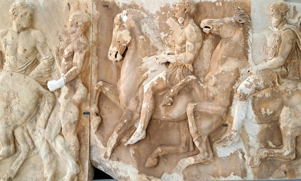 Detailed view of ancient Greek marble relief depicting riders and horses.