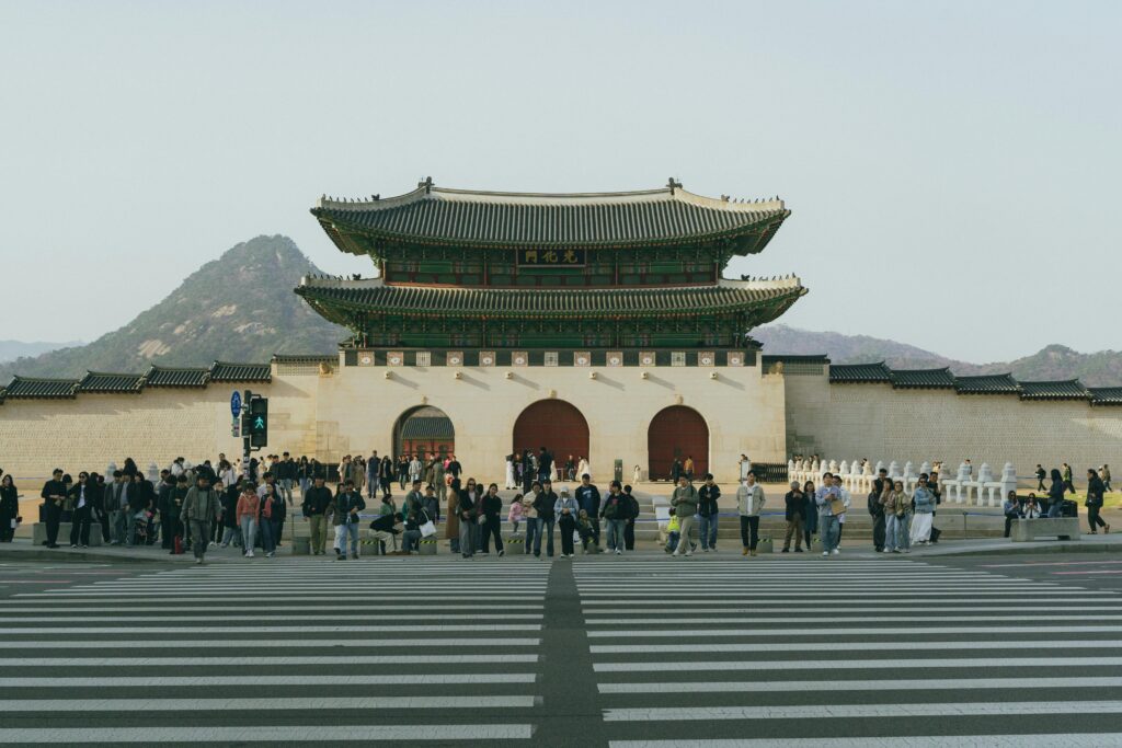 Gwanghwamun Gate with a gathered crowd in Seoul, South Korea, during the day.