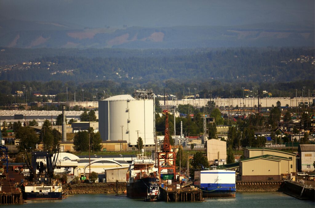 Aerial view of an industrial port with cargo ships, cranes, and warehouses.