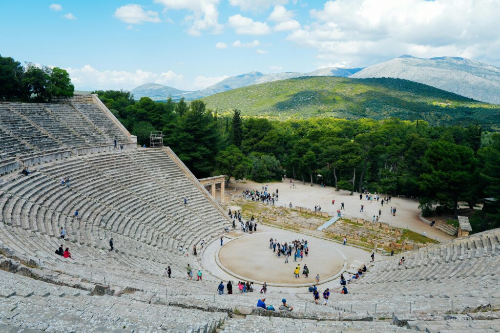 View of the ancient Theater of Epidaurus during a sunny day, with tourists exploring.