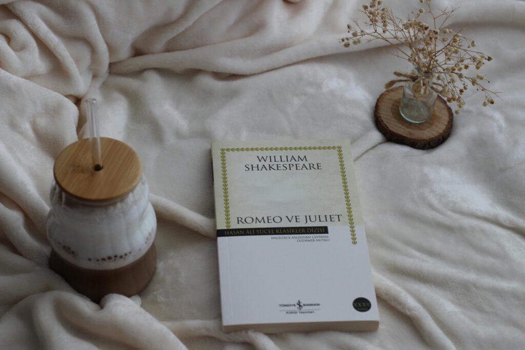 A serene indoor scene with a Romeo and Juliet book, coffee and dried flowers.