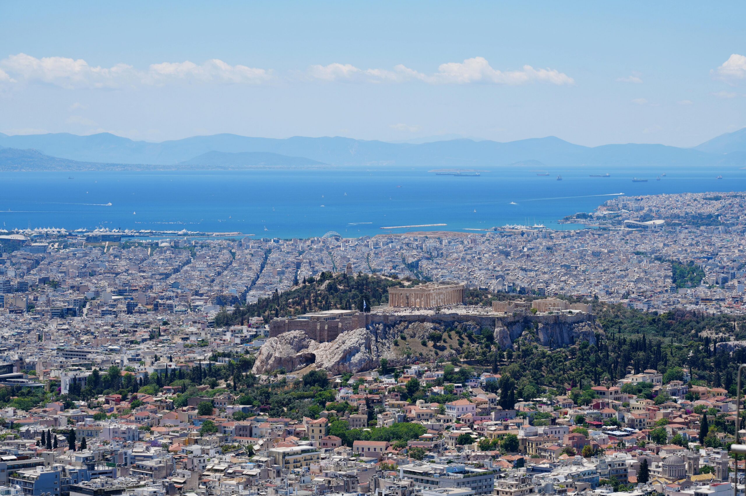Stunning aerial panorama of Athens with the iconic Acropolis and the Aegean Sea in the background.