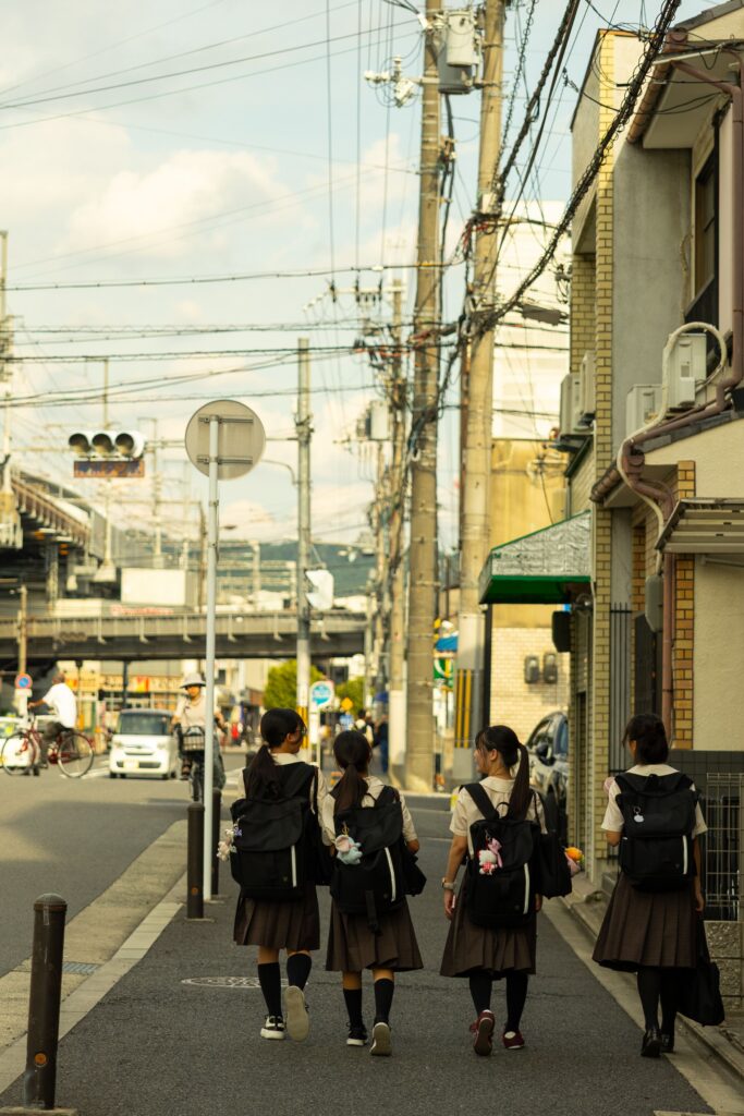 Four schoolgirls in uniform walking down a street in Kyoto, Japan.