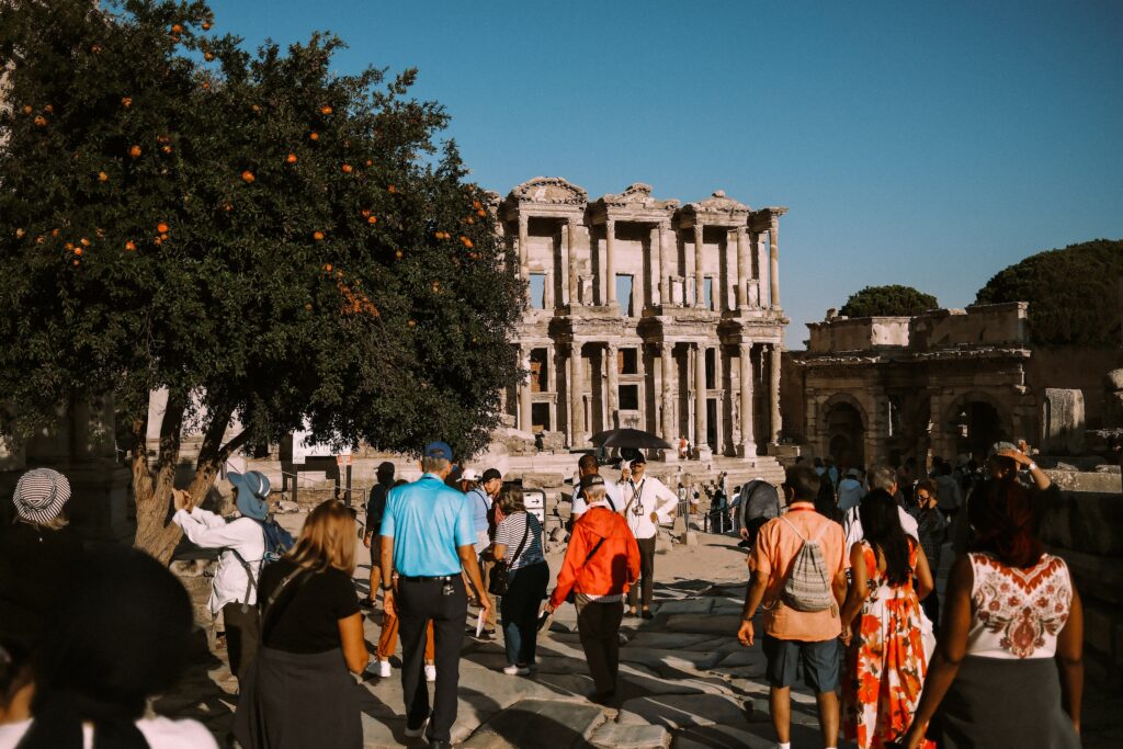 Group of tourists enjoying a sunny day exploring the ancient ruins at Ephesus with vibrant greenery.