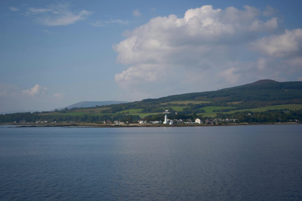 Tranquil summer landscape of the Isle of Bute in Scotland with water, hills, and village.