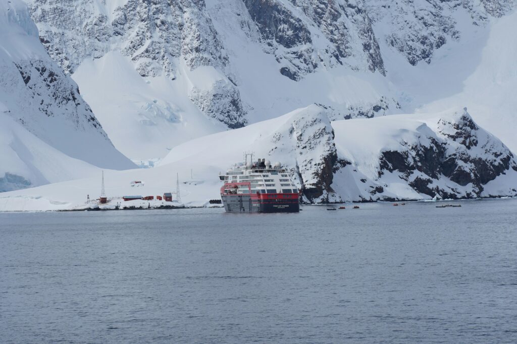 A cruise ship navigating through icy waters surrounded by majestic Antarctic icebergs.