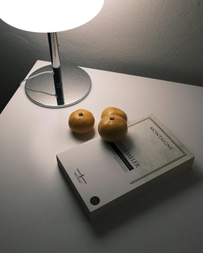 Lemons and book on a minimalist desk with a warm lamp light.