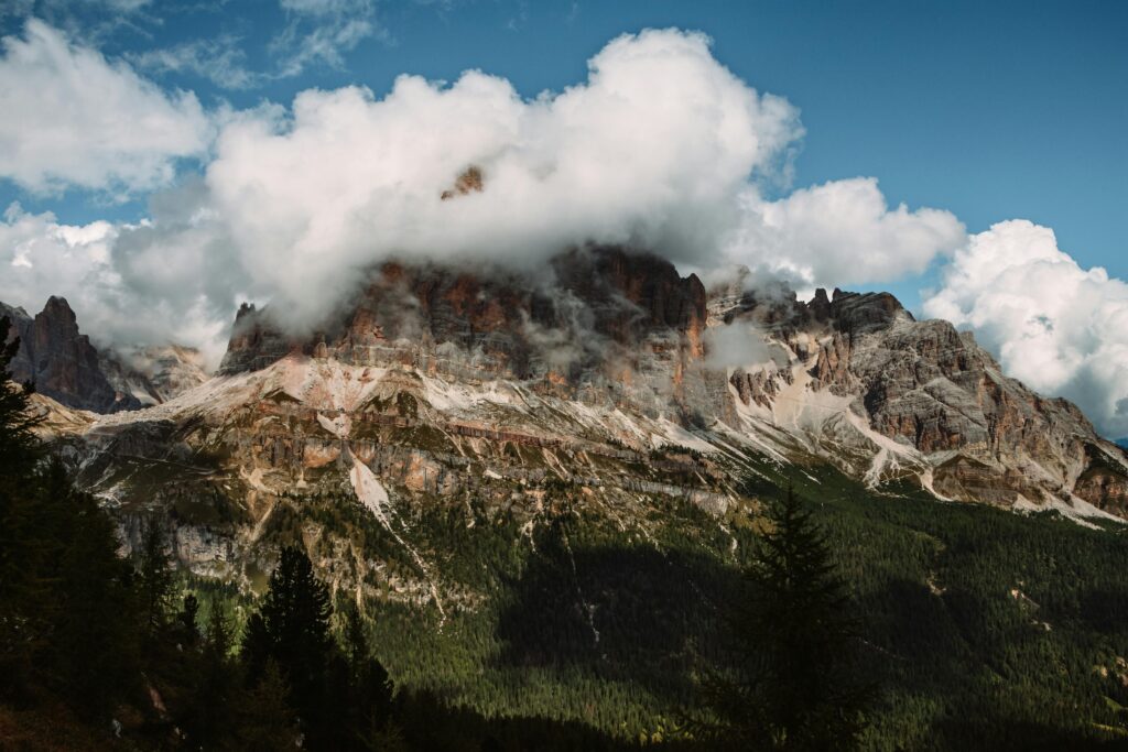 Majestic Dolomite mountains covered in clouds on a clear summer day.