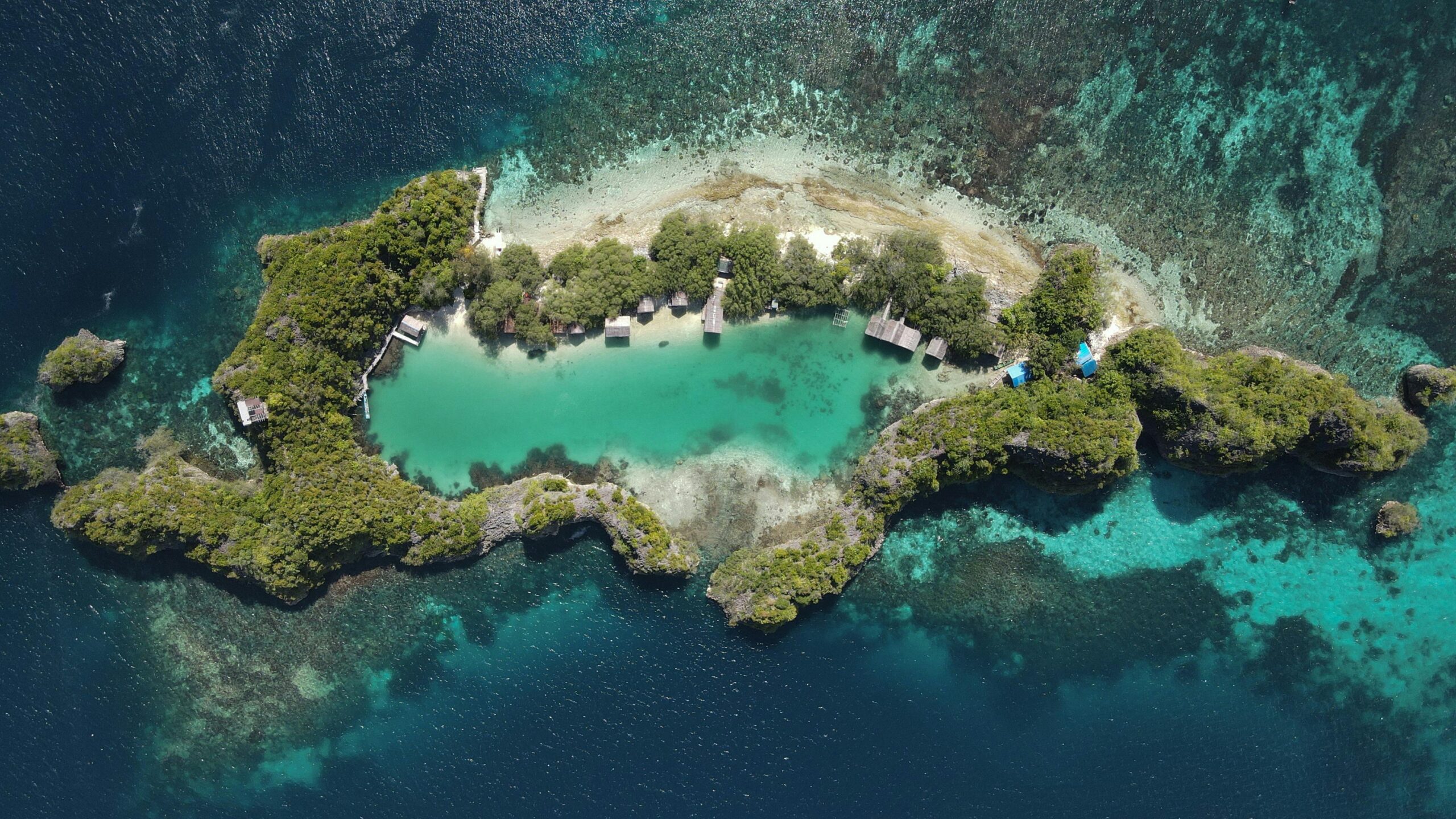 Stunning aerial view of a tropical island lagoon with lush greenery and clear blue waters.