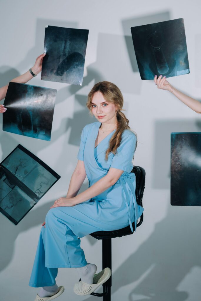 A female healthcare worker in scrubs surrounded by X-ray images in a studio setting.