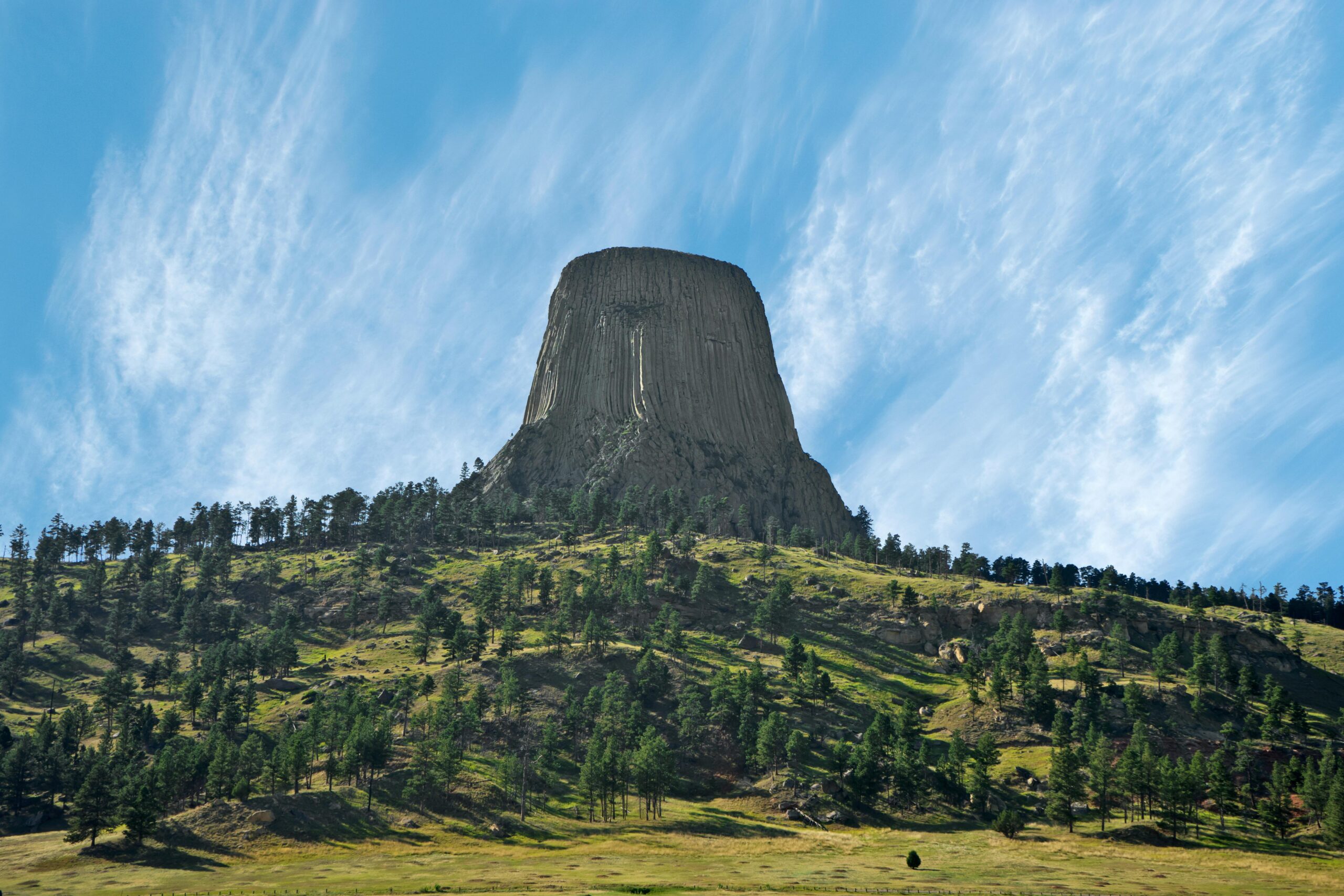 Stunning landscape of Devils Tower in Wyoming, showcasing its iconic rock formation against a clear blue sky.