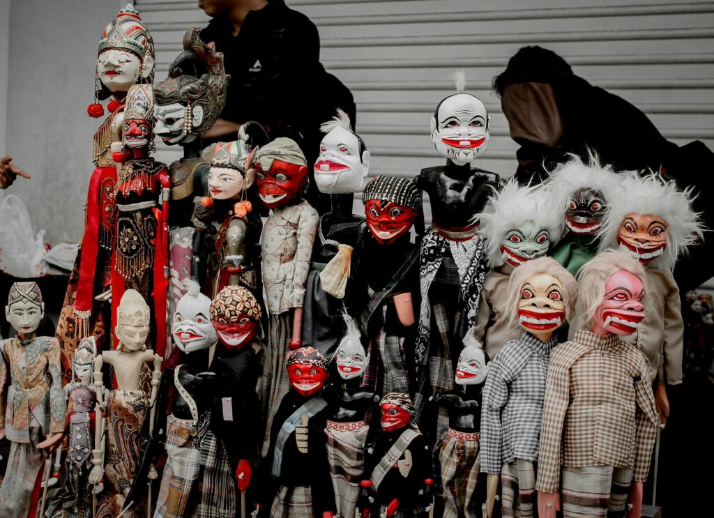Unique collection of vibrant traditional puppets with expressive faces on display outdoors.