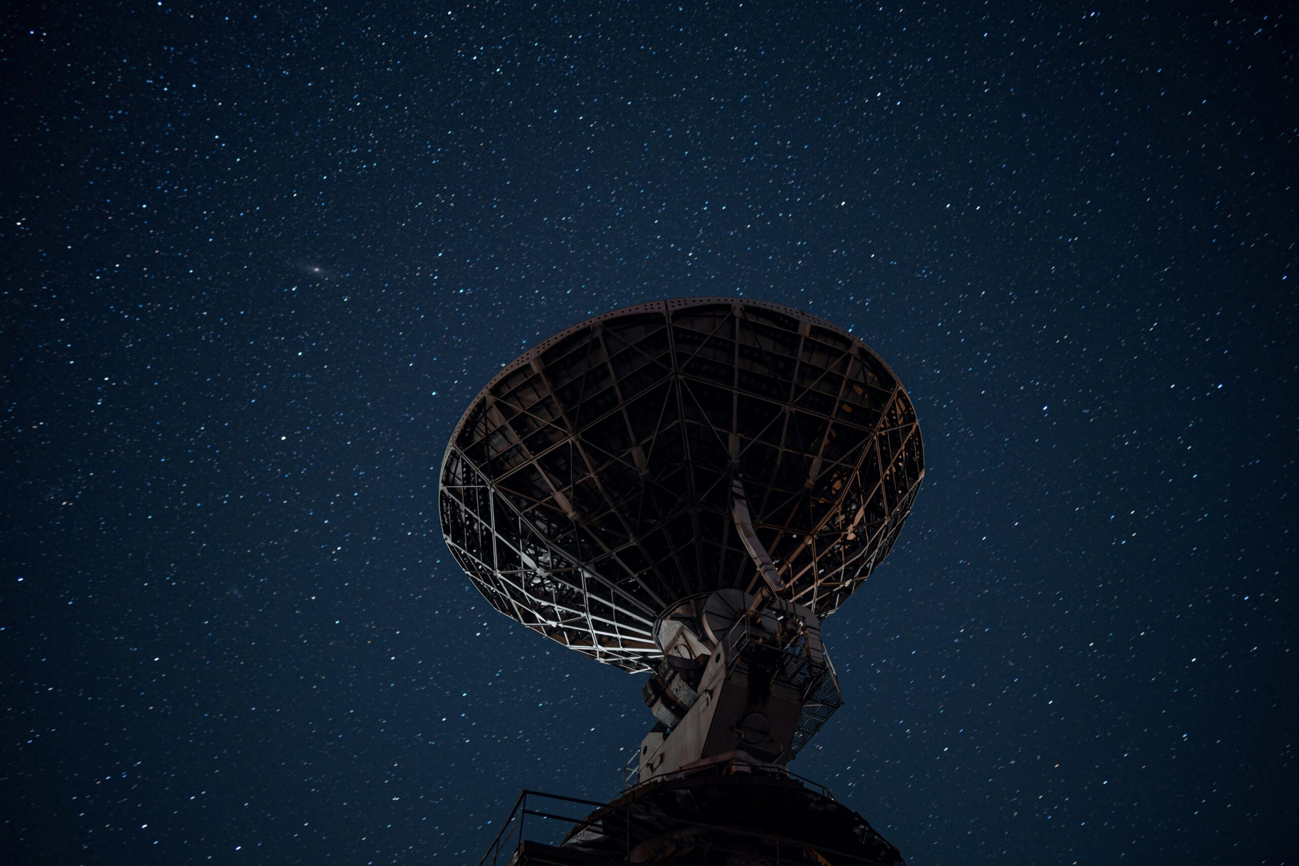 From below of high radio telescope under sky with glowing stars in dark night