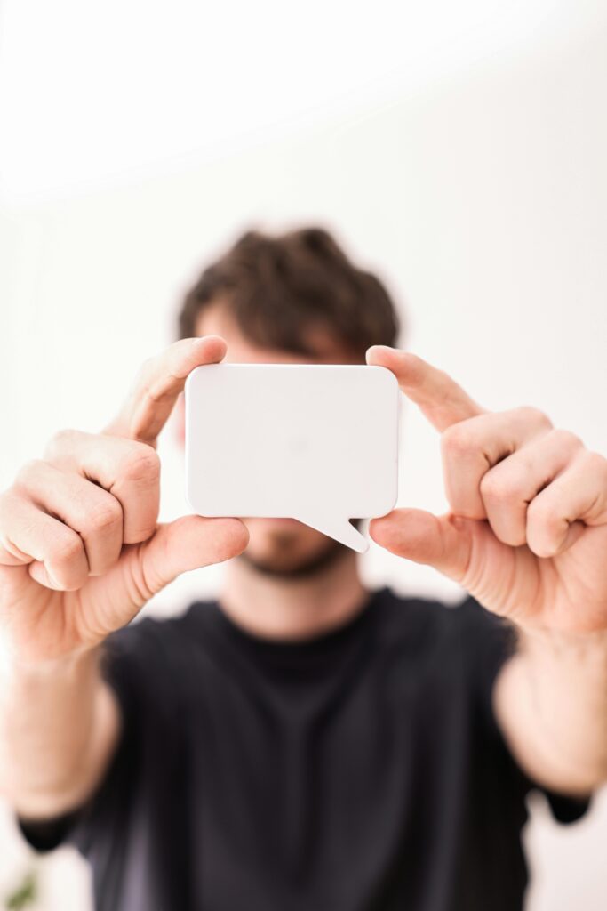 Male holding a blank speech bubble card with both hands, focus on object.