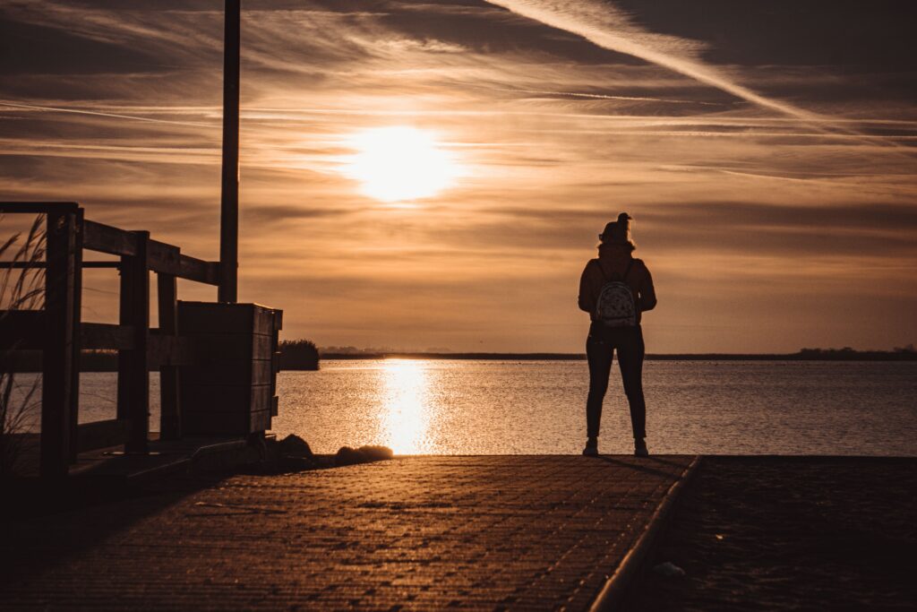 A person stands silhouetted against a stunning sunset over Velence Lake, Hungary.
