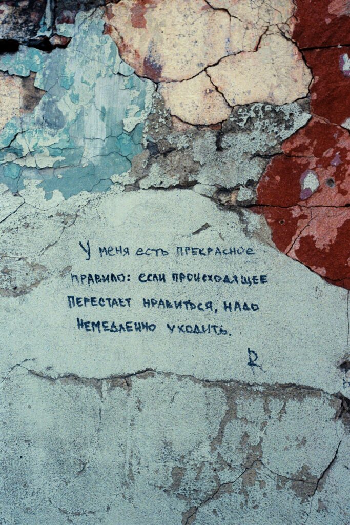 Close-up of a cracked, weathered wall with Russian handwritten text.