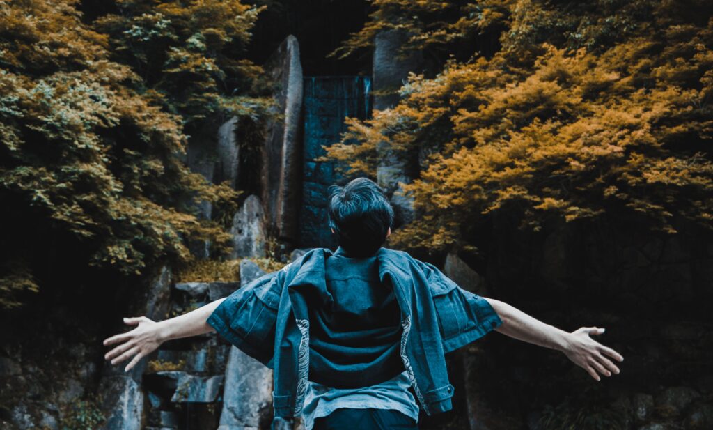 A man enjoying the scenic waterfall and lush autumn foliage in Takahashi, Okayama, Japan.