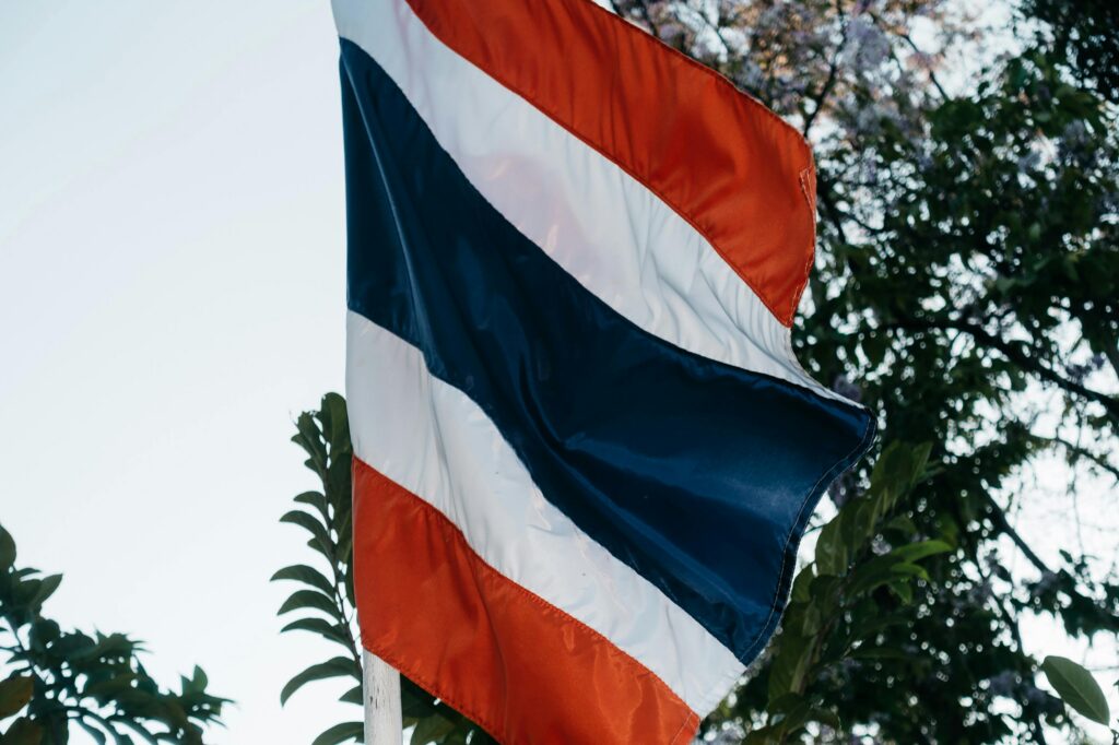 Close-up view of the Thailand national flag waving among trees. Symbolic and patriotic imagery.