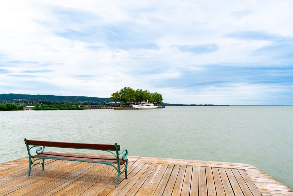 Peaceful scene of a bench on a pier at Lake Balaton in Keszthely, Hungary.