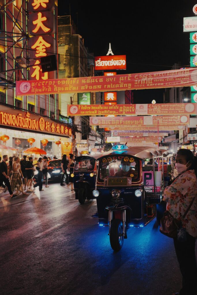 Colorful tuk-tuks and busy streets illuminate Bangkok's vibrant Chinatown at night.